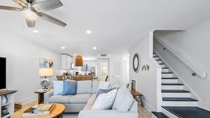 A modern living room with a sofa, coffee table, and a staircase. - Remodeled Seagrove Condo ~ Pool ~ Steps to Beach + Free Attraction Tickets! (Santa Rosa Beach)