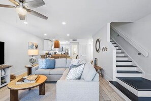 A modern living room with a sofa, coffee table, and a staircase.