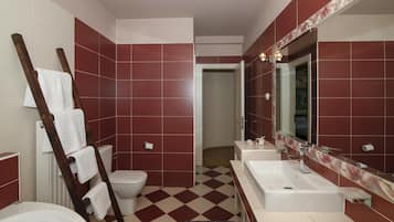 Un baño con baldosas rojas y blancas, una bañera blanca, un inodoro blanco y un espejo grande sobre el lavabo.