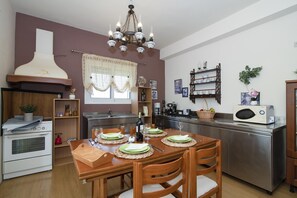 Eine moderne Küche mit einem Esstisch für vier Personen, einem eingebauten Backofen und einer Mikrowelle.