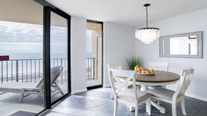 Un balcón con vista al océano, una mesa de comedor con sillas y un candelabro.