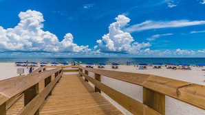 A wooden boardwalk leading to a sandy beach with blue umbrellas and people relaxing. - 4BR, Beachfront, 3RD FLOOR - Parking level!, Waterslide! (Gulf Shores)