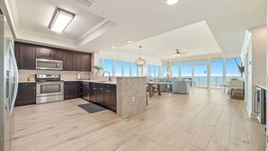 A modern kitchen with dark cabinets, stainless steel appliances, and a large island. - 4BR, Beachfront, 3RD FLOOR - Parking level!, Waterslide! (Gulf Shores)