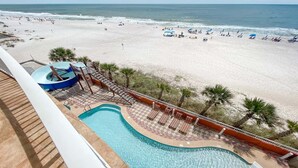 A pool area with a water slide, lounge chairs, and a view of the beach. - 4BR, Beachfront, 3RD FLOOR - Parking level!, Waterslide! (Gulf Shores)