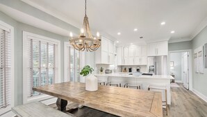 Une cuisine moderne avec des meubles blancs, un îlot central en bois et un lustre.