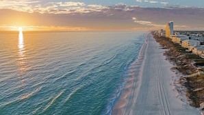 Un paysage urbain côtier avec une longue plage, des bâtiments et un ciel dégagé.