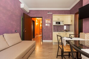 A modern living room with a sofa, dining table, and kitchen area.