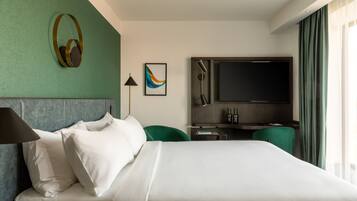 Habitación de hotel con cama, escritorio, televisión, lámpara y pared verde.
