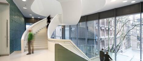 Un interior moderno con una escalera curva, ventanas amplias y vistas al exterior.