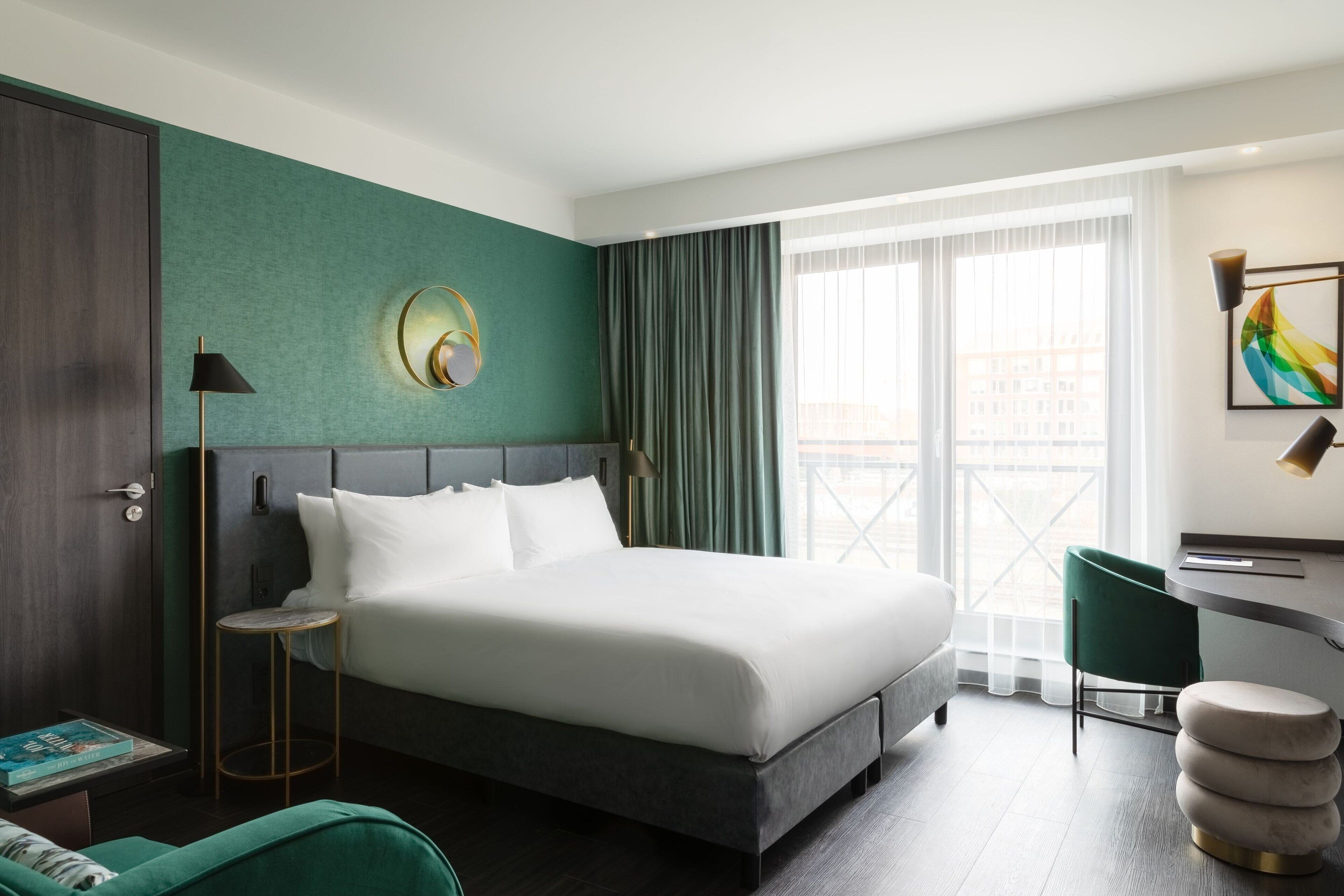 Ein modernes Hotelzimmer mit einem großen Bett, einem Schreibtisch und Blick auf die Stadt.