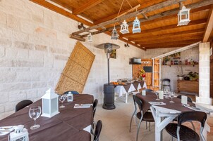 Un comedor rústico con mesas y sillas de madera, un muro de piedra y faroles colgantes.
