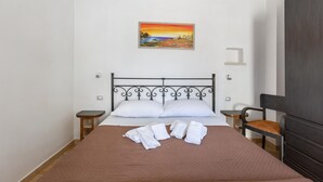 A neatly made bed with white linens, a brown quilt, and a painting of a sunset on the wall. - 2487 B&B Mariano - Camera Matrimoniale (Ceglie Messapica)