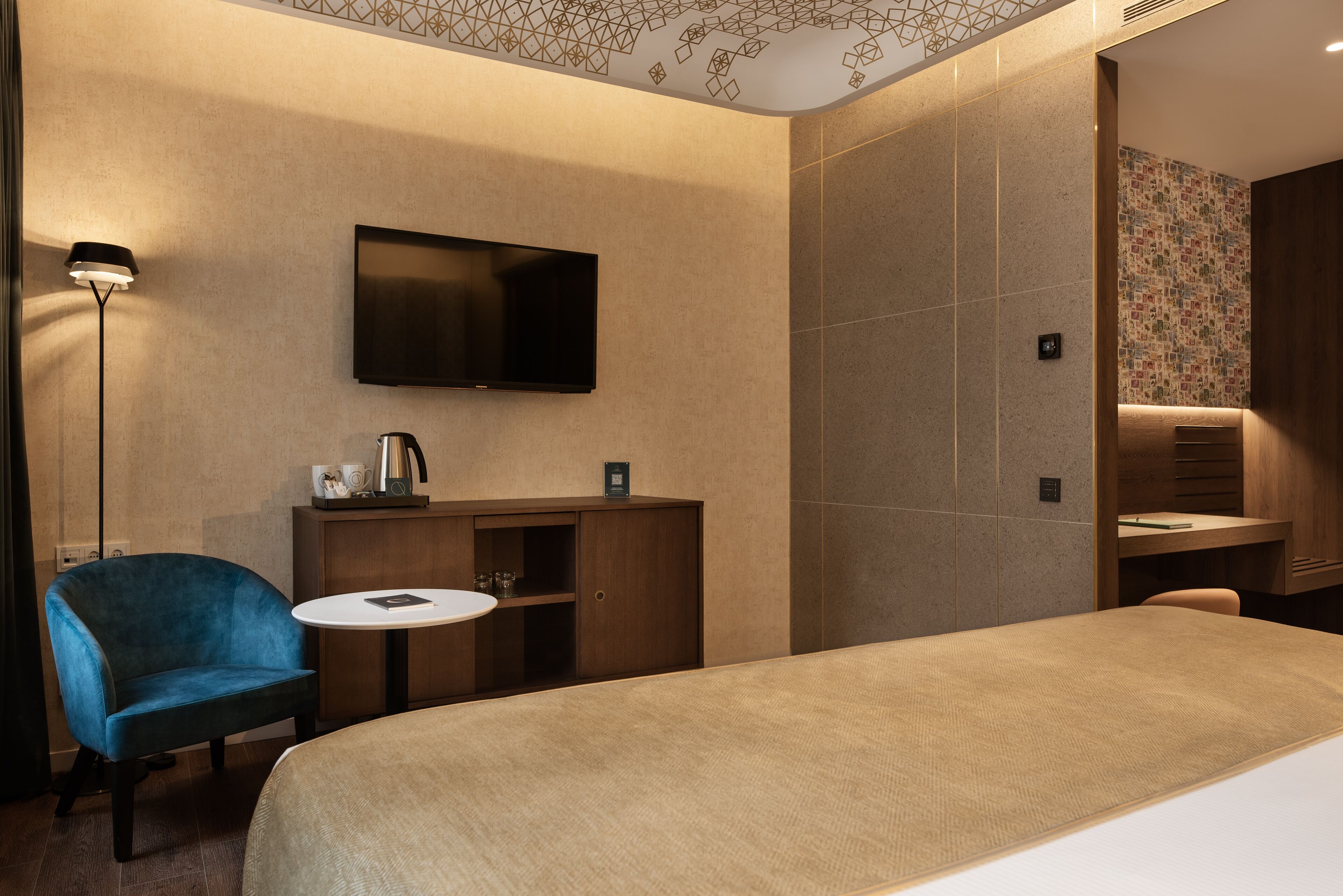Ein Hotelzimmer mit Bett, Schreibtisch, Stuhl, Fernseher und kleinem Tisch.