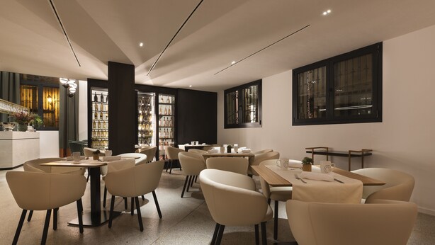 A modern restaurant interior with round tables and chairs, a bar area, and a view of the city through large windows. - Áurea Palacio de Correos by Eurostars Hotel Company (Logroño)