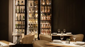 Ein Restaurant mit Weinkeller, Ledersesseln und einem gedecktem Holztisch.