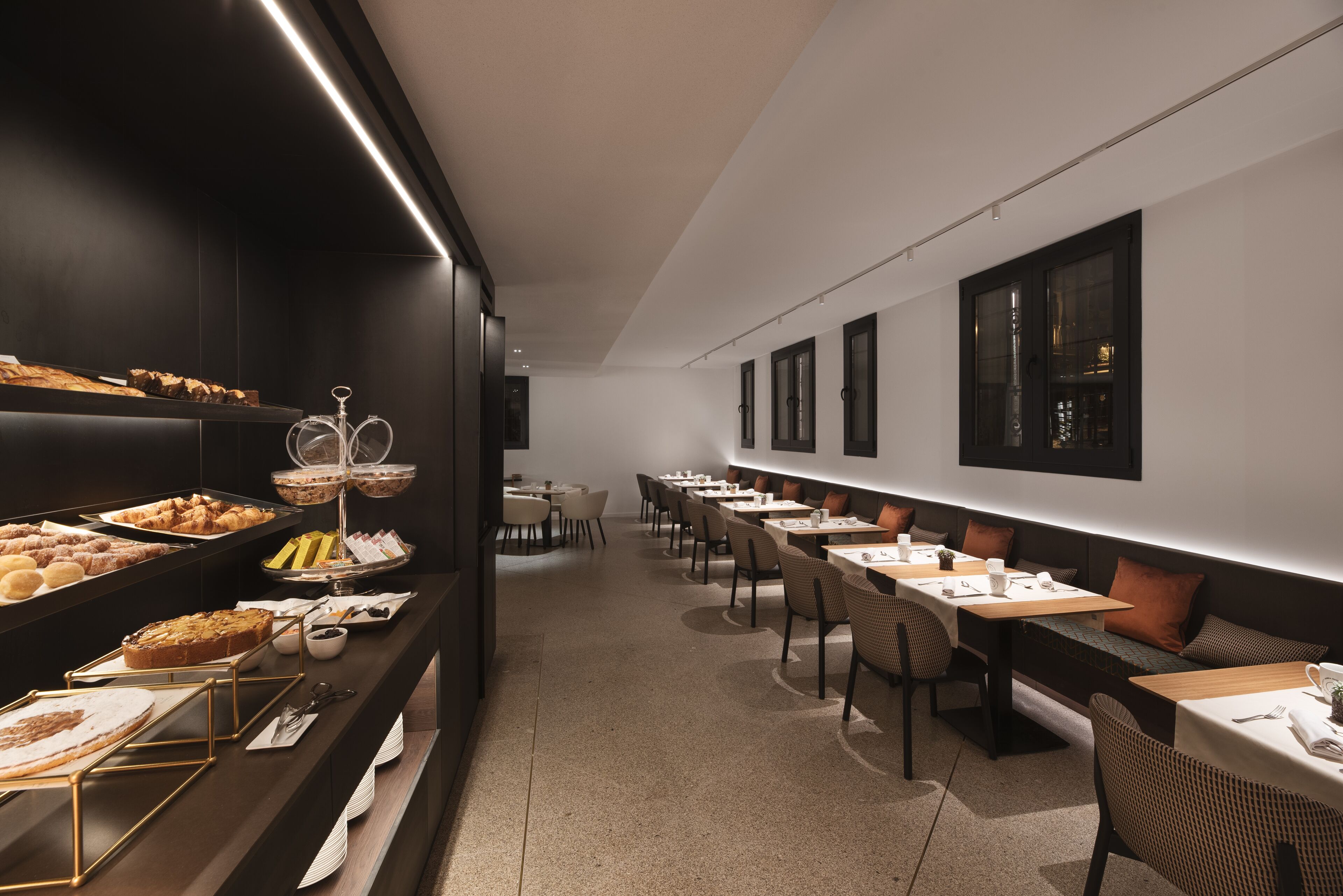Un comedor moderno con estaciones de comida tipo bufé y diversas disposiciones de asientos.