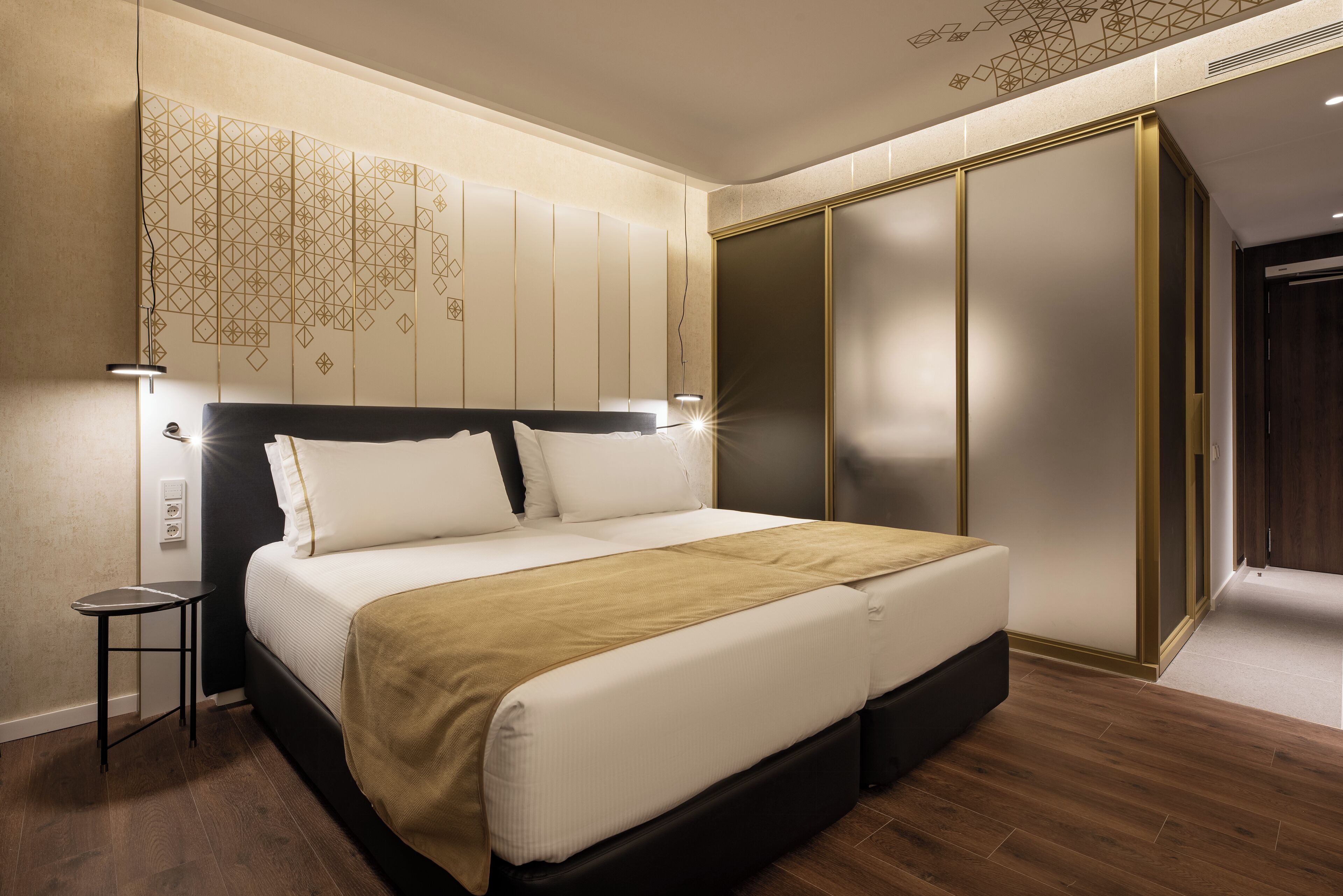 Een moderne slaapkamer met een groot bed, een nachtkastje, een kledingkast en een decoratief wandpaneel.