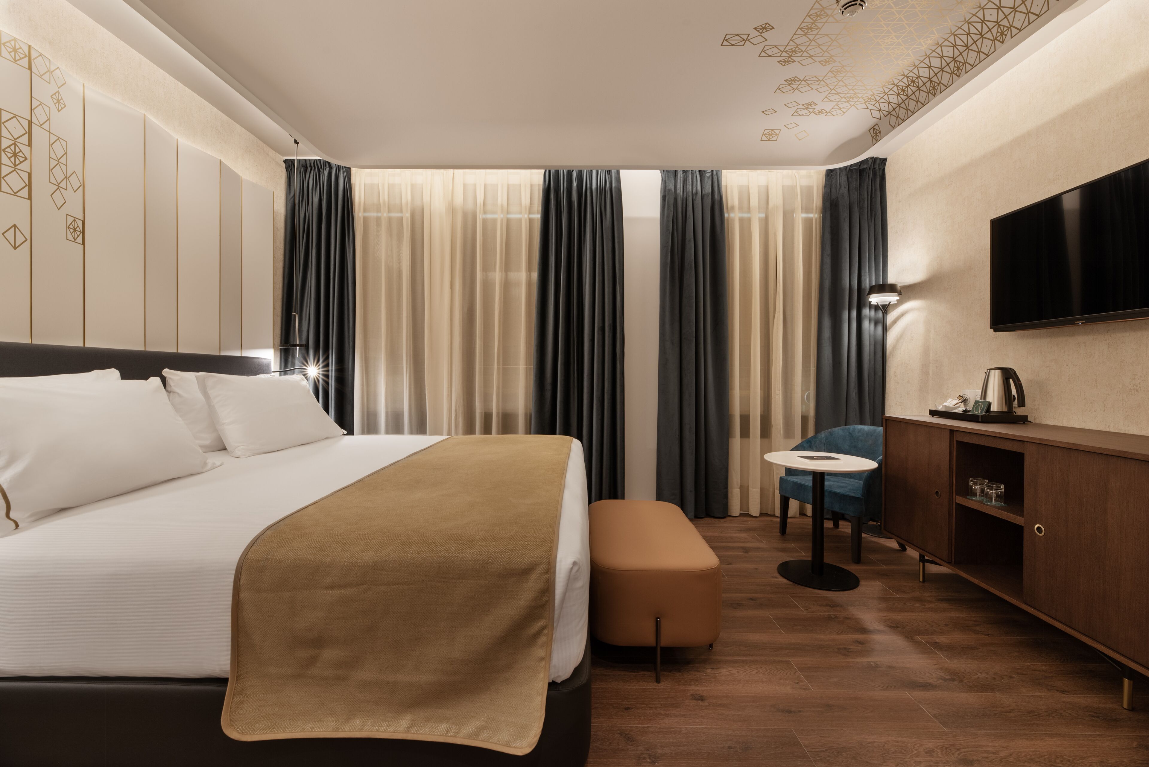 A hotel room with a bed, a desk, a chair, a television, and a coffee maker.