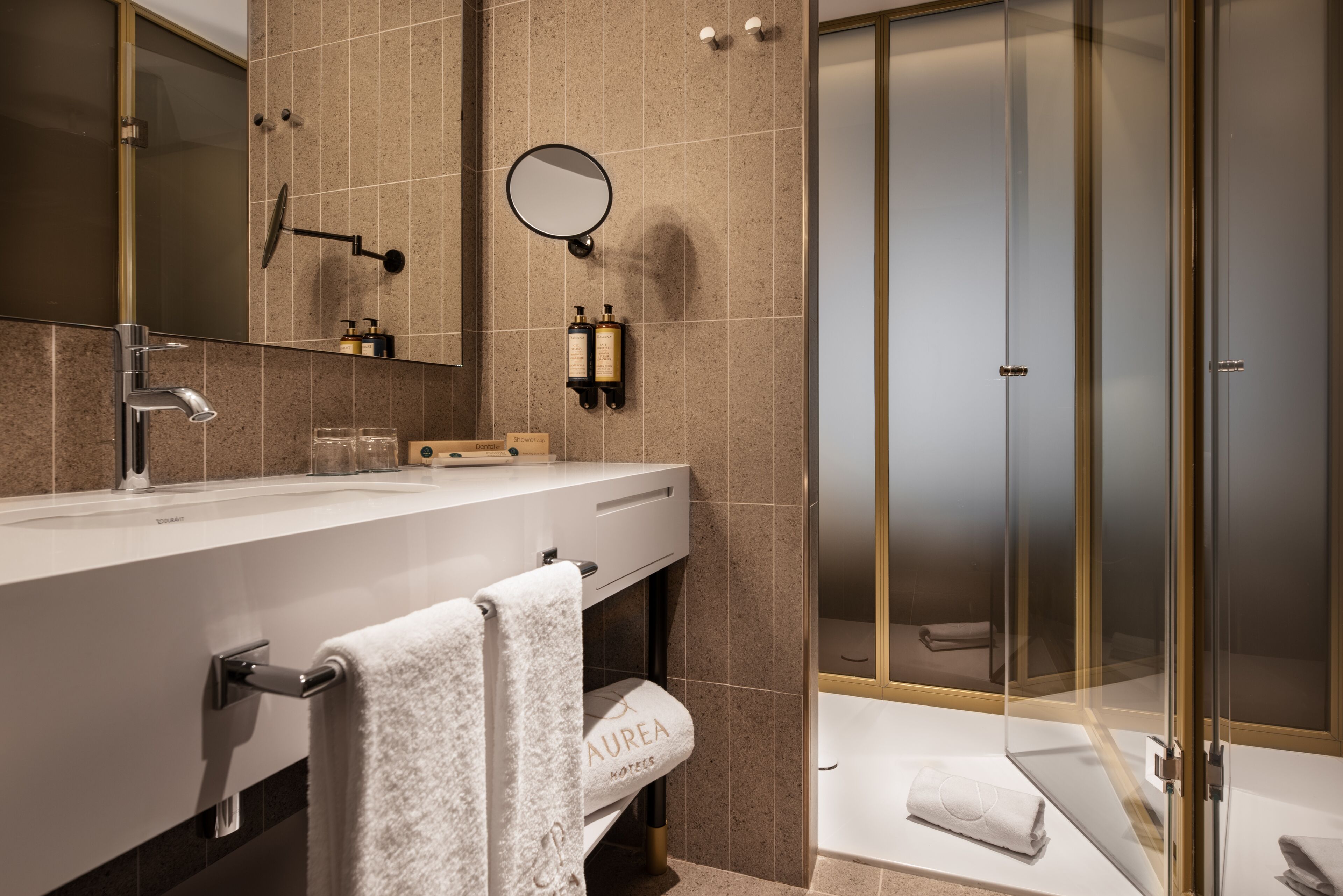 Un baño moderno con un espejo grande, un lavamanos y una ducha con mampara de vidrio.