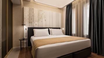 Habitació d'hotel moderna amb un llit gran, una taula de nit, televisió penjada a la paret i una finestra amb cortines.