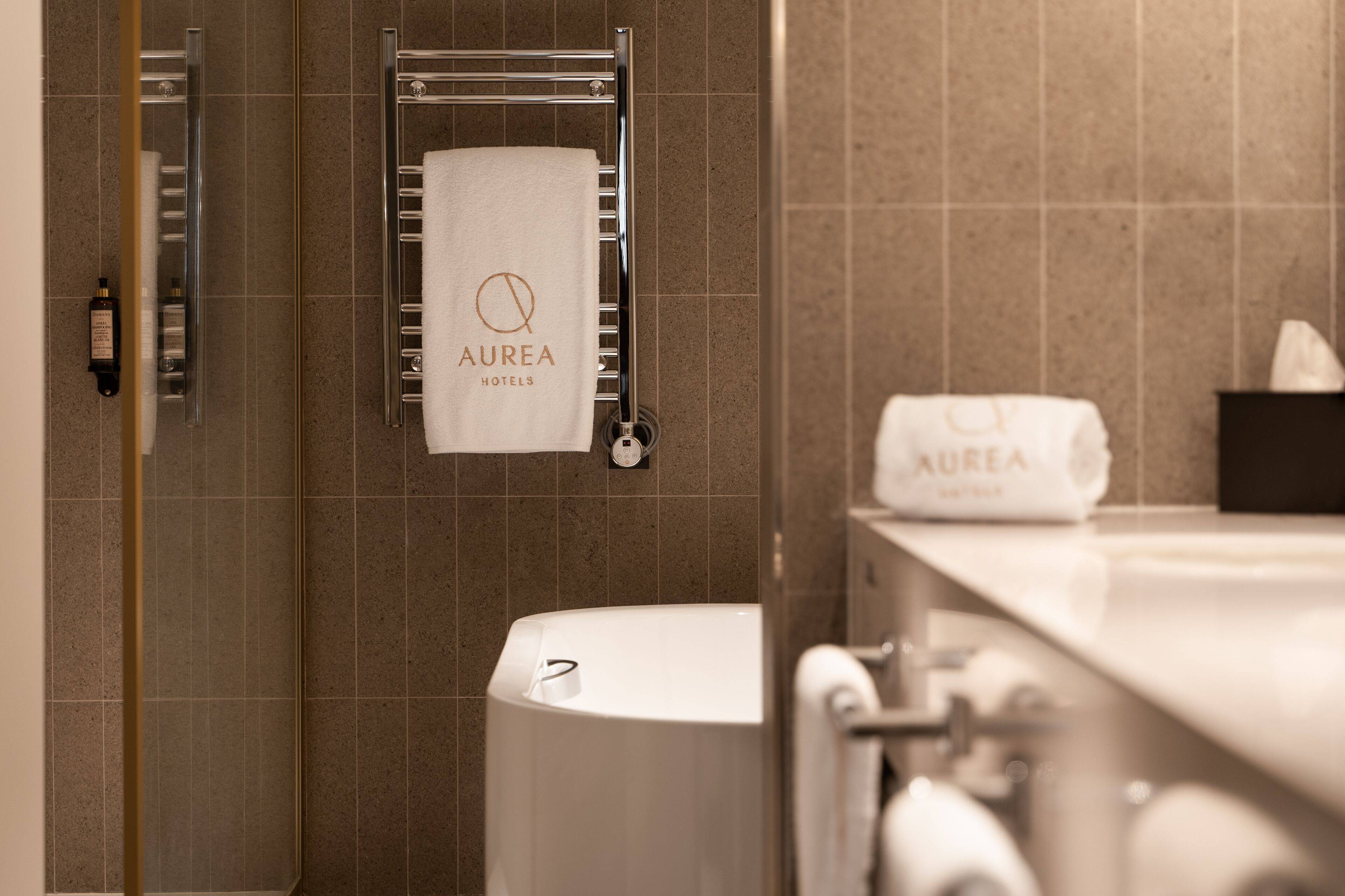 Un baño con bañera, toallero con toalla y artículos de aseo.