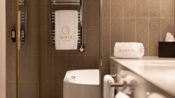 Un baño con bañera, toallero con toalla y artículos de aseo.
