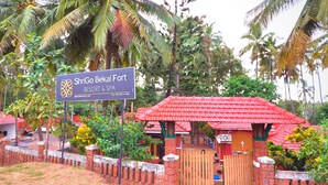 A sign for ShriGo Bekal Fort Resort & Spa, surrounded by lush greenery and a red-roofed building. - ShriGo Bekal Fort Resort & Spa (Hosdurg)