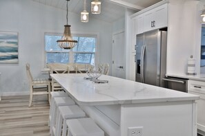 Enjoy cooking in this well-equipped kitchen with a central island, stainless steel appliances, and a large window offering a view of the outdoors.