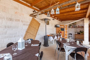 Un comedor rústico con mesas y sillas de madera, un muro de piedra y faroles colgantes.