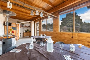 Un interior de madera con un comedor listo para una comida, con mesas, sillas y faroles colgantes.