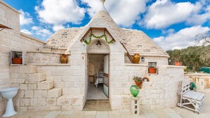 Un edificio de piedra con techo cónico, una puerta y un pequeño porche.