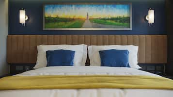 A hotel room with a large bed, two wall-mounted lights, and a painting above the bed.