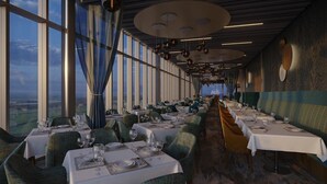 A restaurant with long tables, chairs, and a view of the cityscape through large windows. - Hotel La Tour (Milton Keynes)