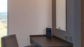 Una habitación de hotel moderna con escritorio, silla y un espejo grande.