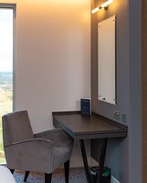 Una habitación de hotel moderna con escritorio, silla y un espejo grande.