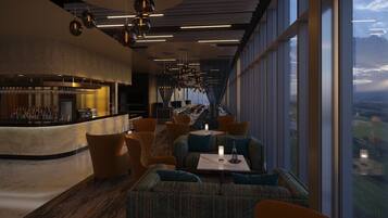A modern interior with a bar area, seating with cushions, and large windows offering a view.