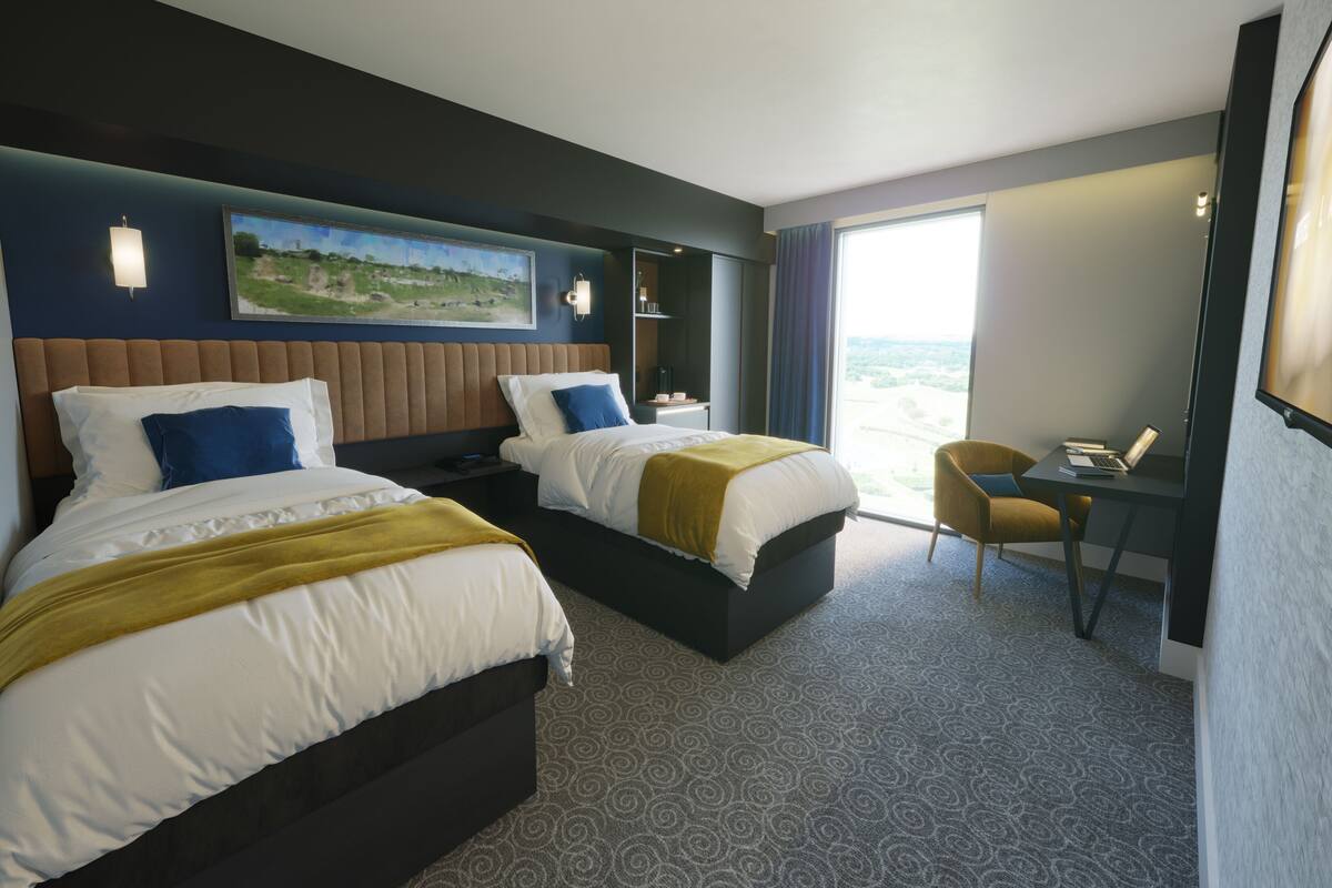 A hotel room with two beds, a desk, and a chair.