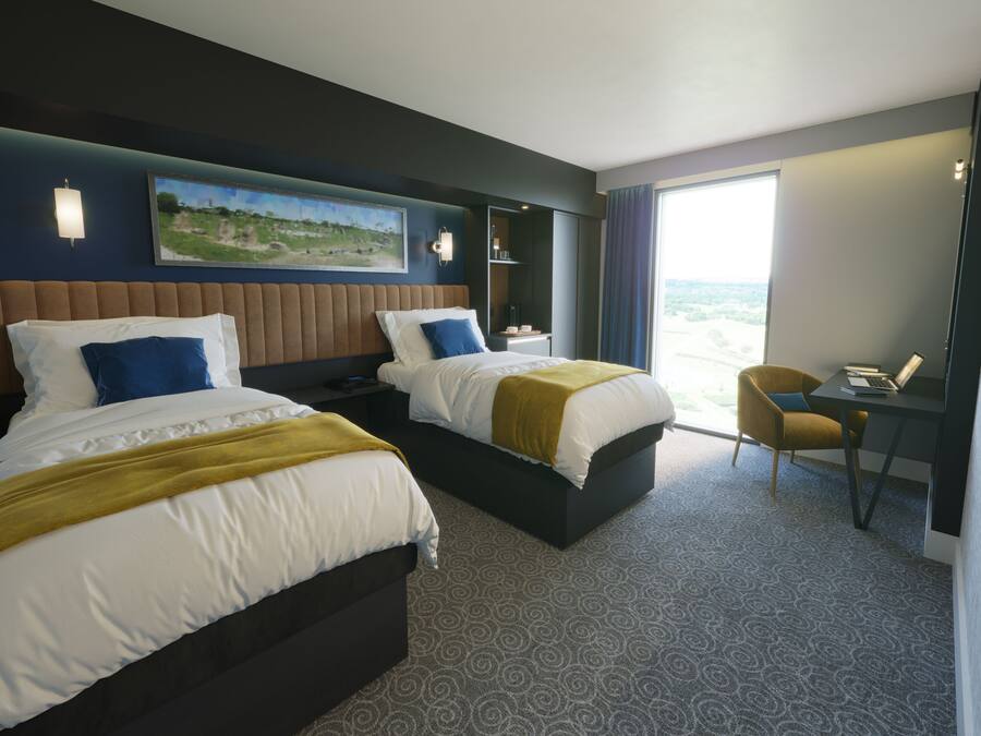 Une chambre d’hôtel avec deux lits, un bureau et une chaise.