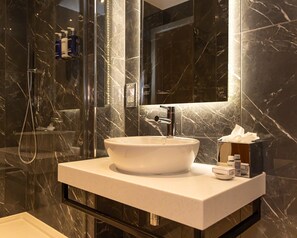 A bathroom with a white sink, a mirror, and toiletries on the counter.
