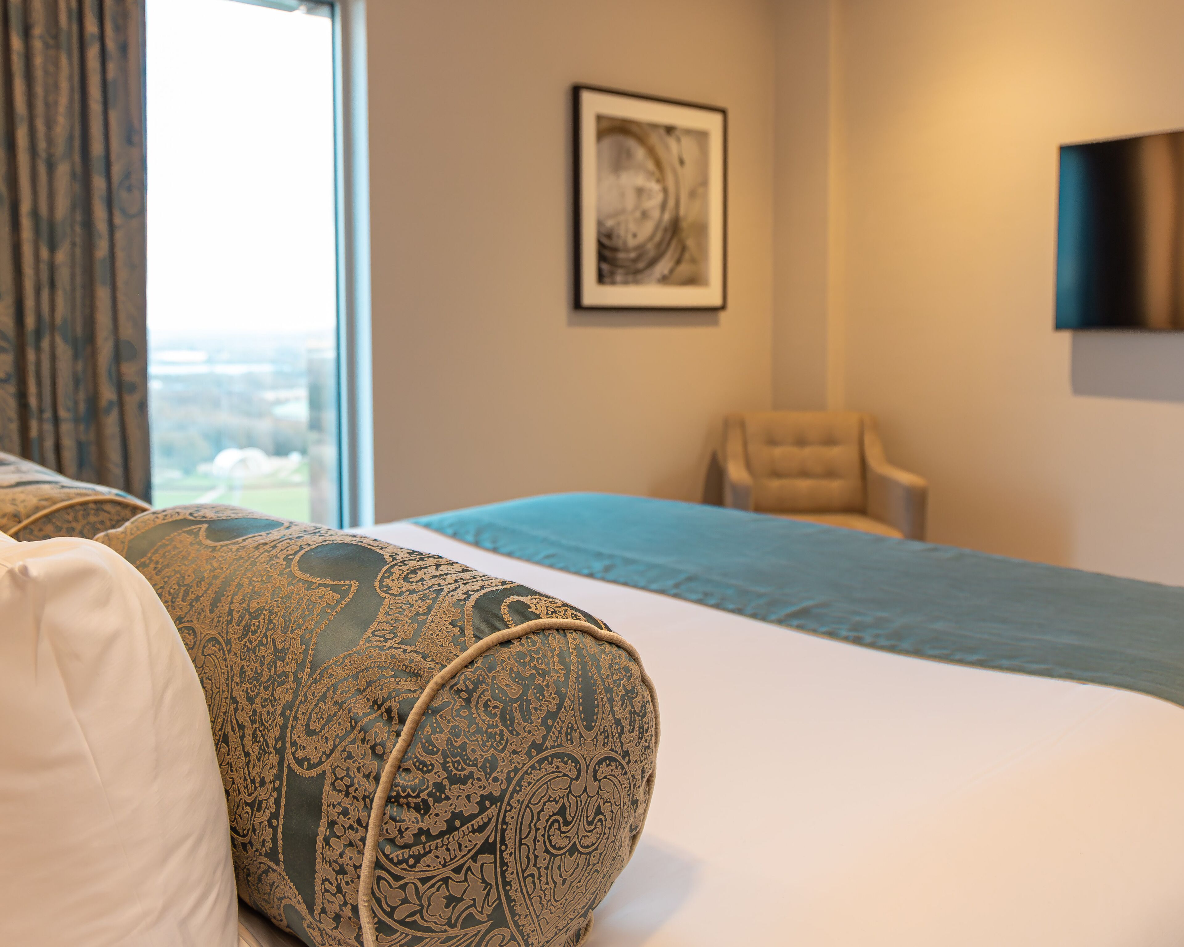 Una habitación de hotel con cama, una silla y ventana con vistas.