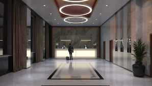 A modern hotel lobby with a reception desk, marble walls, and a large potted plant. - Hotel La Tour (Milton Keynes)