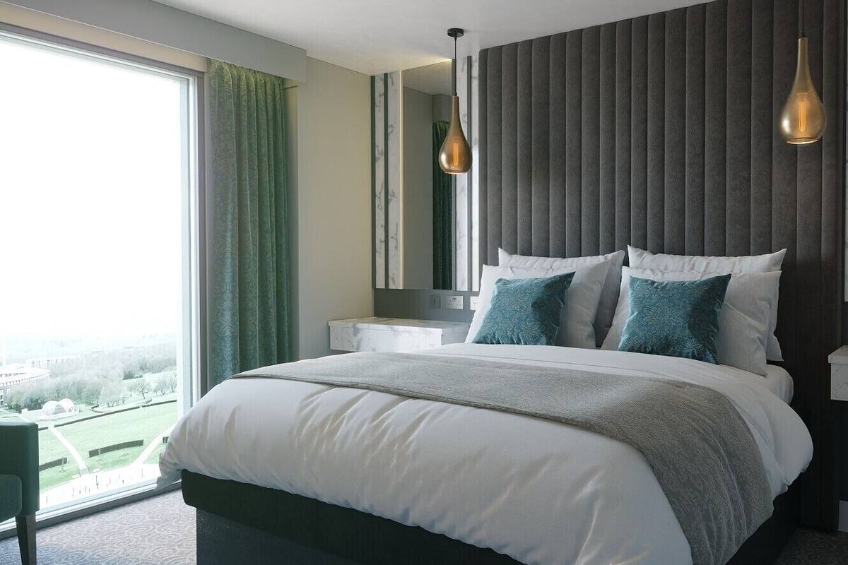 A modern bedroom with a large bed, a nightstand, a chair, and a view of a green landscape through a large window.
