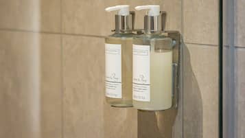 Dos botellas de champú y acondicionador 'Lime & Bay' en un dispensador de pared en un baño con paredes de azulejos.
