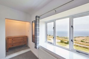 A bedroom with a large window, a wooden dresser, and a radiator. - Host & Stay | Fairview House (Ravenscar)