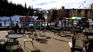 Un espace extérieur aménagé avec des tables et des chaises, offrant une vue sur un paysage enneigé et une piste de ski.