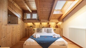 Une chambre aux murs lambrissés, dotée d’un puits de lumière, d’un lit avec des serviettes, d’un radiateur et d’une petite fenêtre.