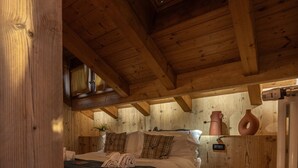 Une pièce chaleureuse avec un lit, une cheminée, des poutres en bois et une fenêtre.