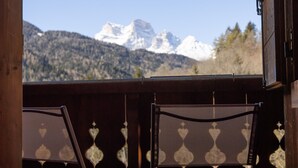 Due sedie su un pontile di legno con vista su montagne innevate.