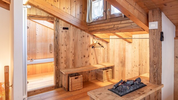 Ambiente in legno con una panca, cesti e un tavolino con un oggetto decorativo.