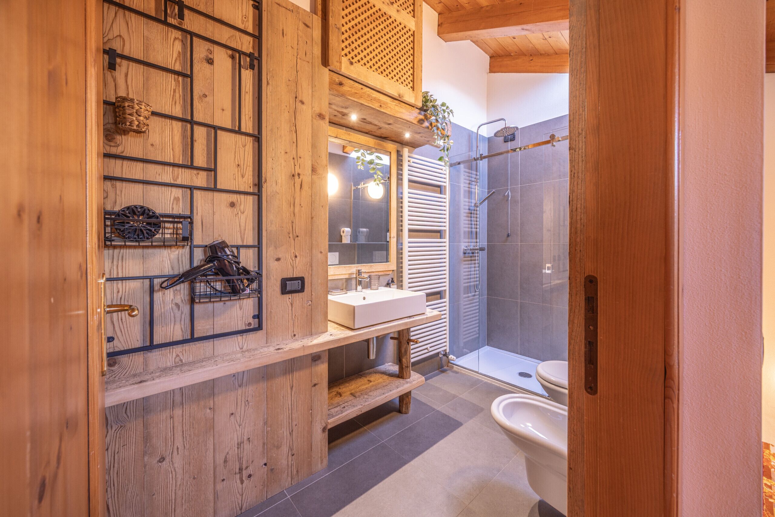 A bathroom with a wooden vanity, a sink, a mirror, and a shower area.